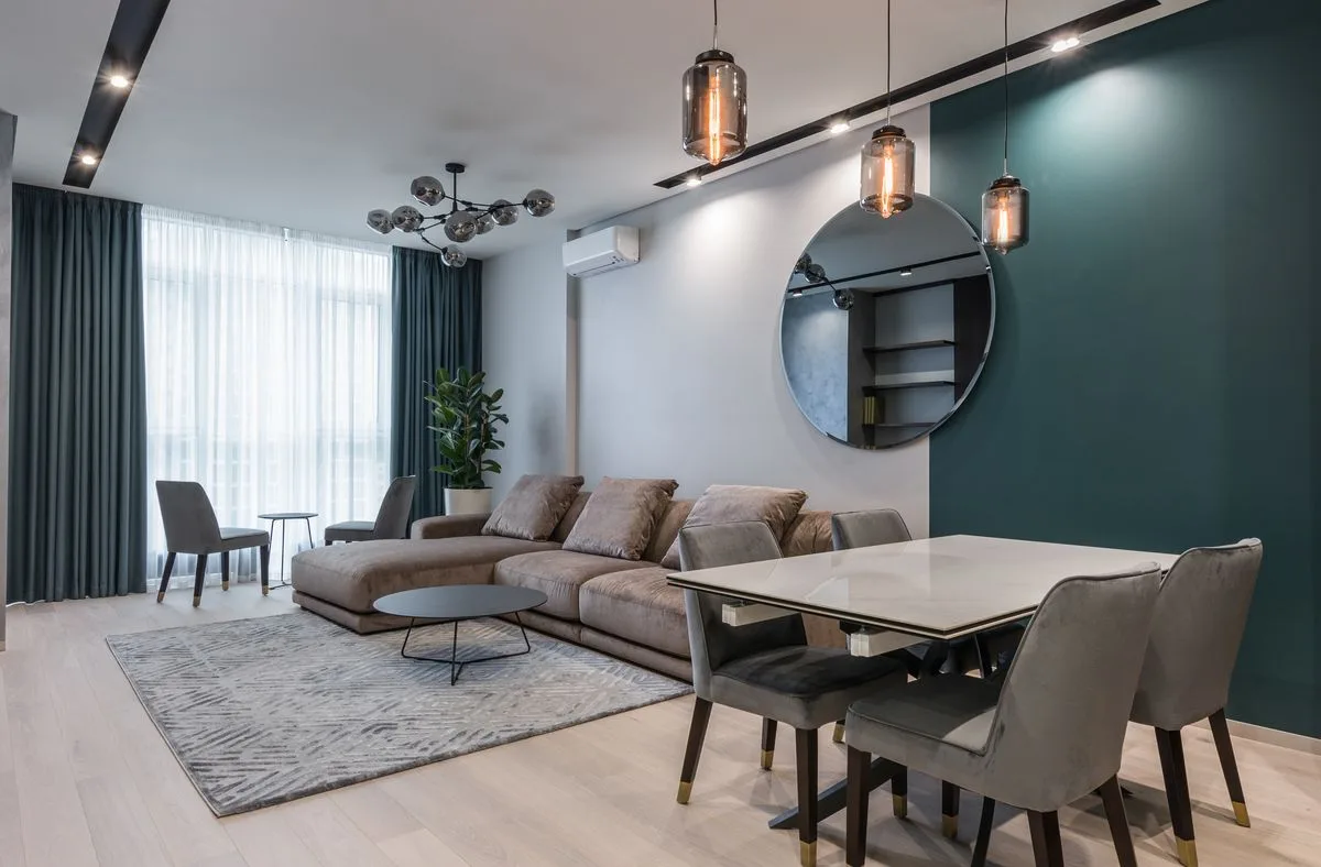 Open living and dining space zoned with a rug and a round wall mirror