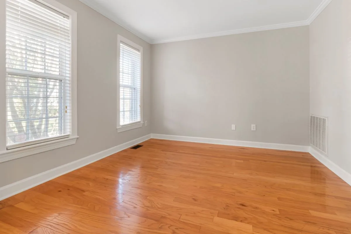 Empty apartment room with wood floors and bright windows