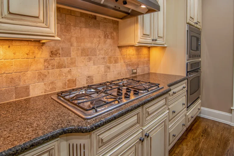 Glass and stone linear mosaic backsplash with stainless steel range hood
