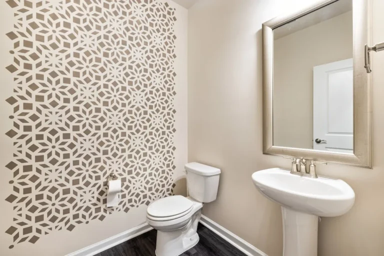 Bathroom with a neutral geometric pattern wallpaper and a pedestal sink