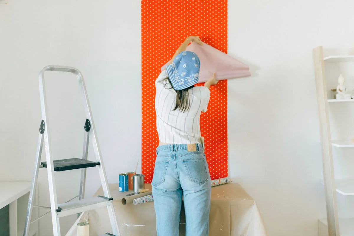 Hands applying a peel-and-stick wallpaper panel using a smoothing tool