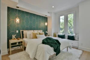Bedroom with a green geometric peel-and-stick wallpaper accent wall behind the bed