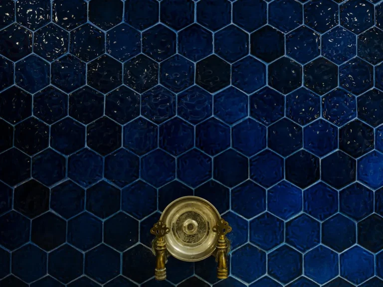 Dark blue hexagonal tile wall with brass fixture