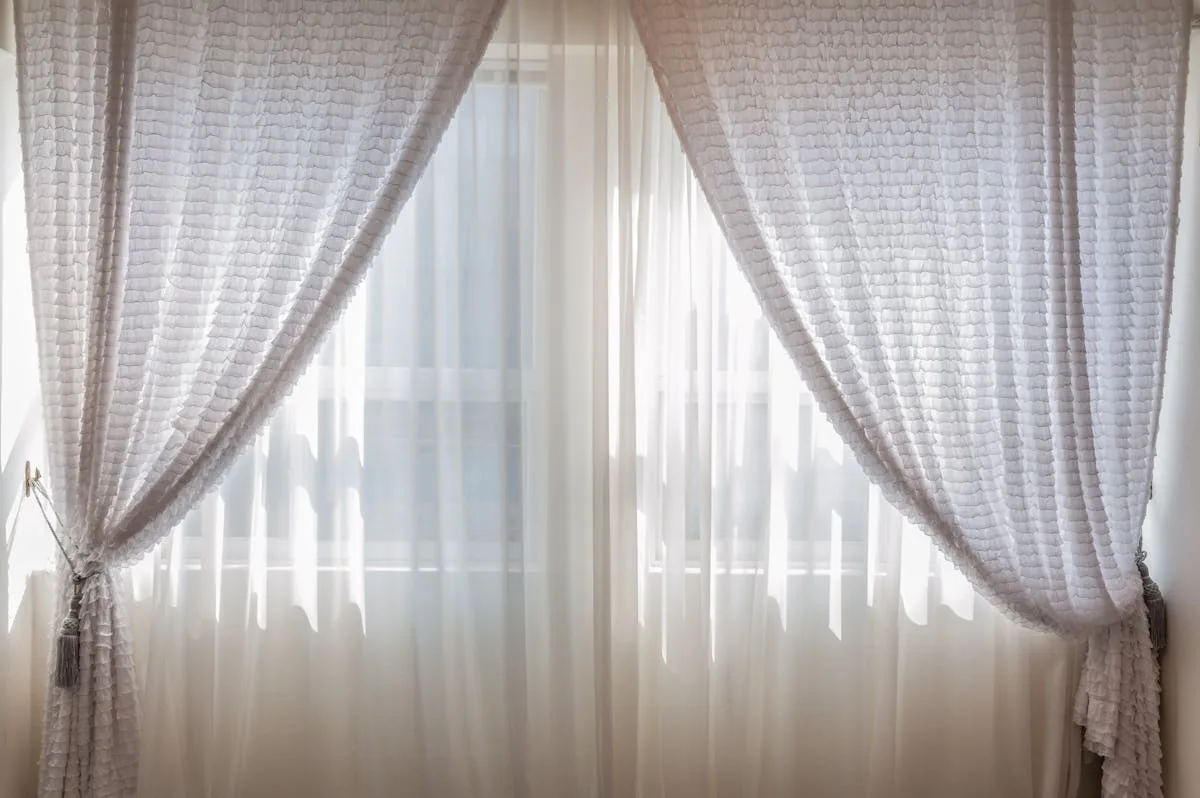 White linen curtains filtering soft daylight at an apartment window