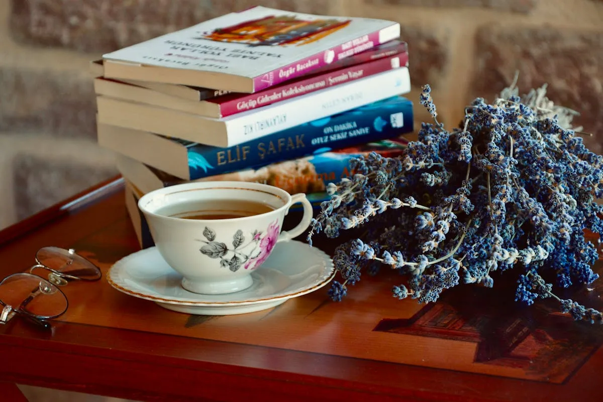 Vintage rosebud teacup beside a stack of books and dried lavender