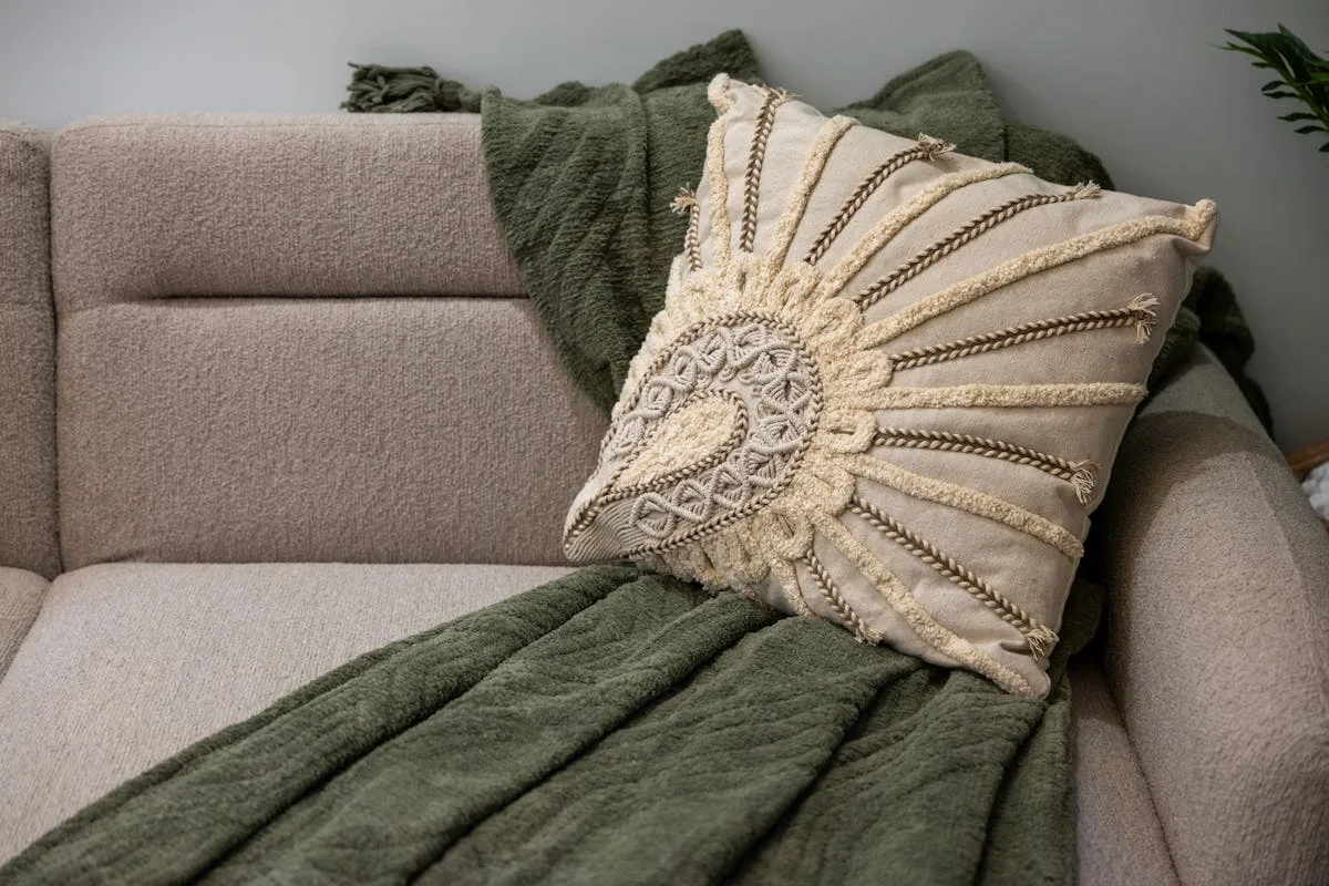 Green knit throw and a textured cushion layered on a neutral sofa