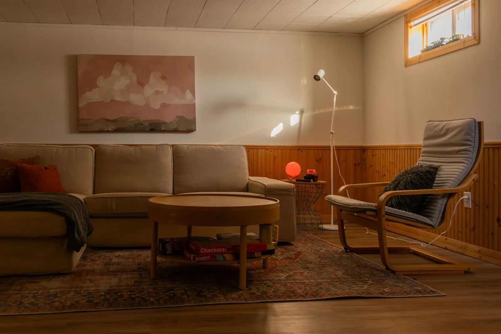 Cozy budget apartment living room lit by a warm floor lamp in the evening