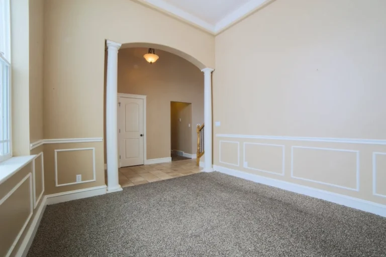 Empty room with white wainscoting columns and crown molding