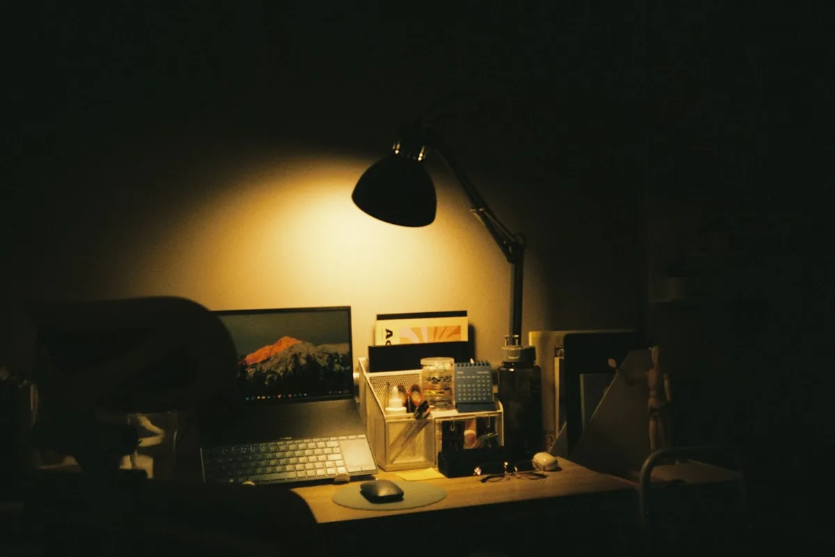 Desk lit only by a warm desk lamp in a dim room