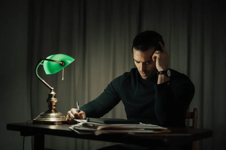 Green banker's desk lamp lighting a dark wood study desk