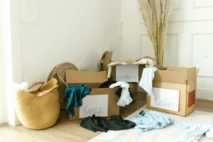 Cardboard boxes labeled keep, donate, and trash with clothes during a declutter