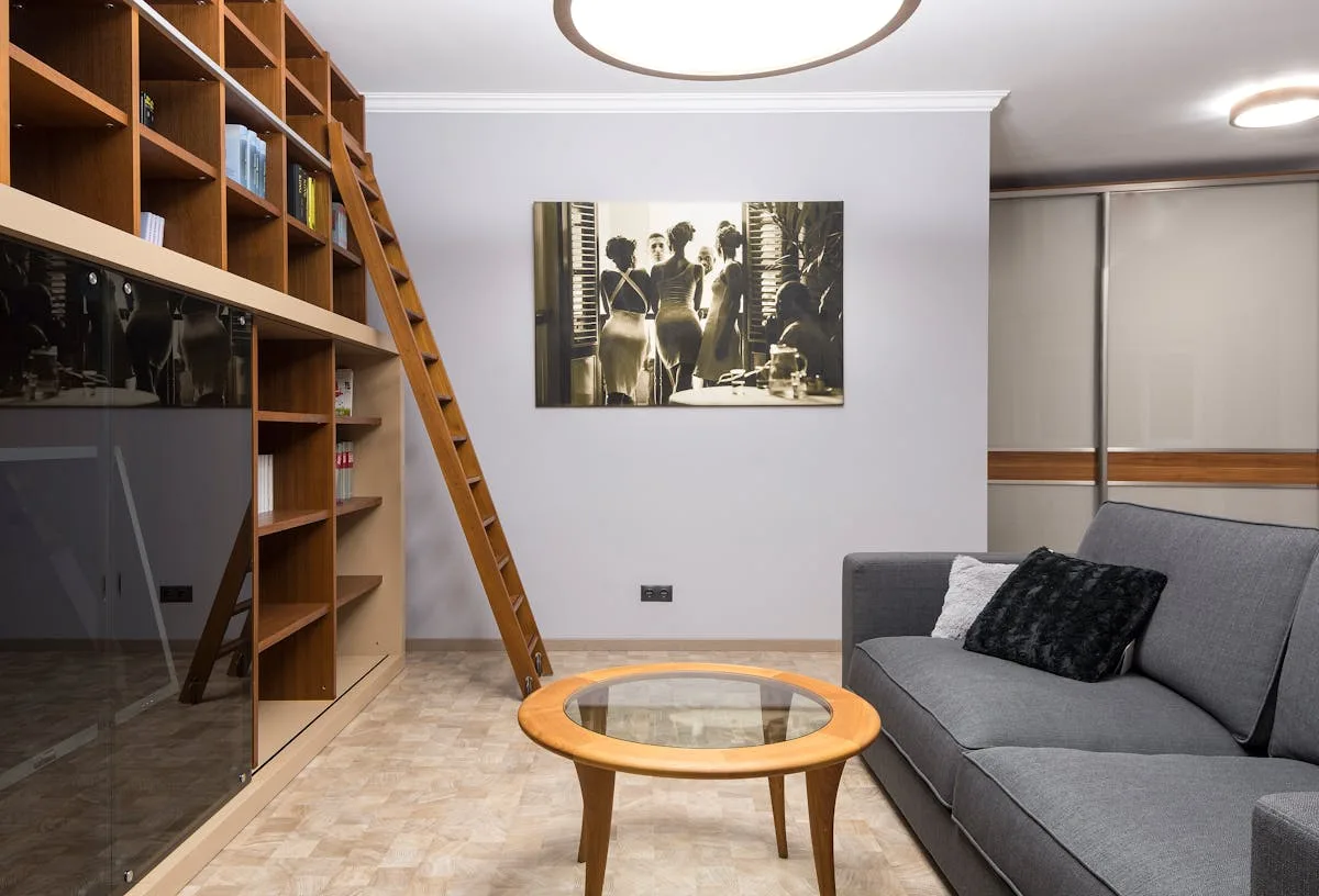 Tall wooden bookshelf wall anchoring a small living room with a grey sofa