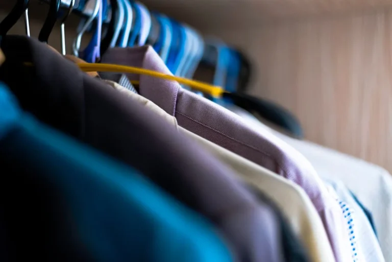 Small closet with clothes on a hanging rod extender