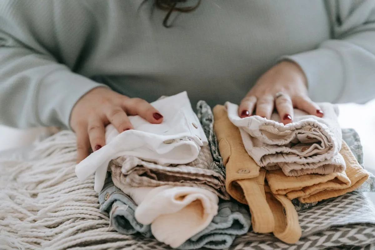 Hands folding neutral clothes into a tidy stack