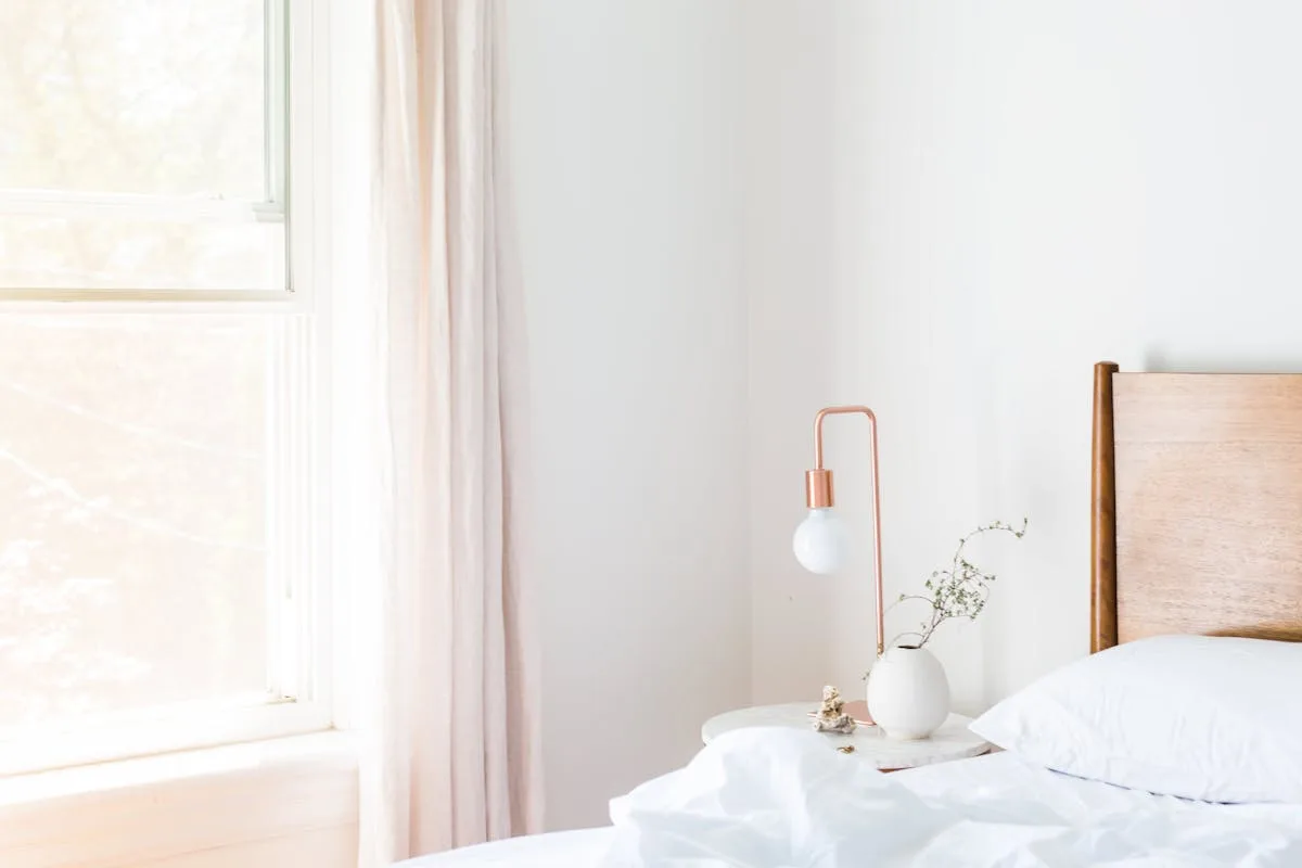 Light japandi bedroom with a wood headboard, linen bedding, and a single branch