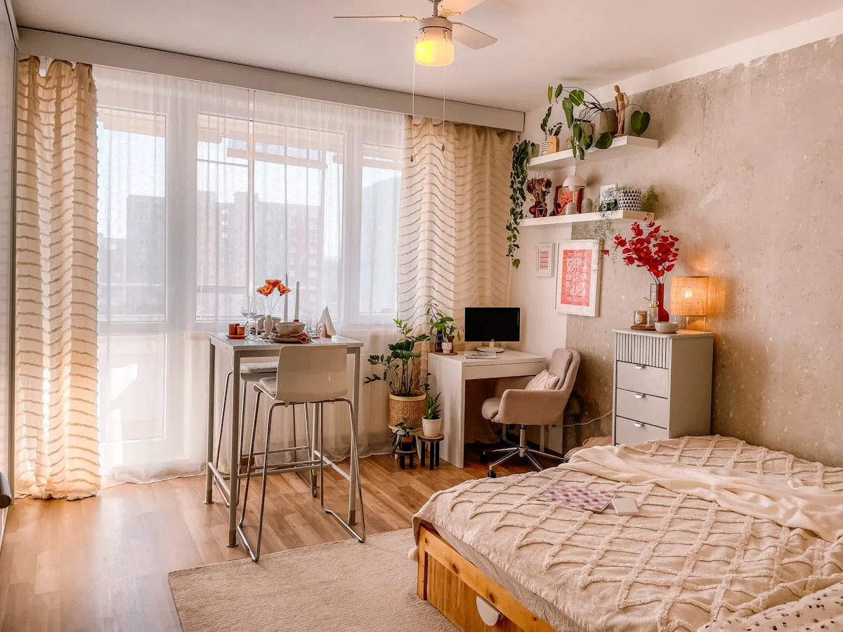 Compact studio bedroom with a bed, a desk workspace and a bar table by the window