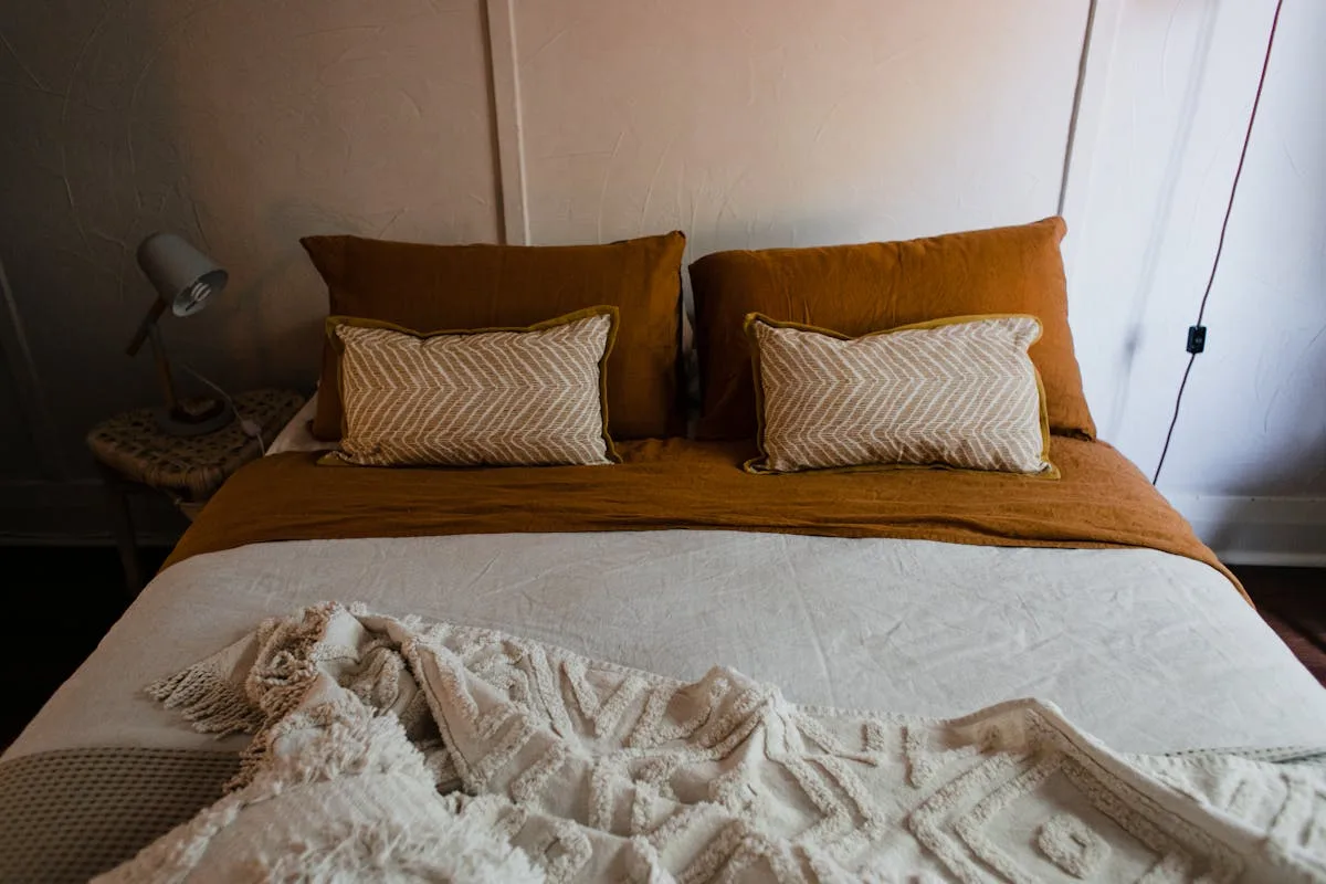 Calm one bedroom apartment bedroom with warm terracotta bedding and a bedside lamp