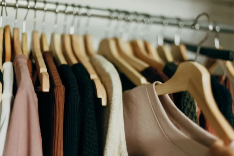 Row of clothes neatly hung on matching wooden hangers in an organized closet