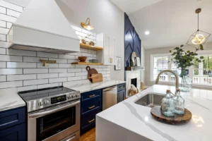 Modern kitchen with white subway tile backsplash above the stove, white marble countertop and navy lower cabinets