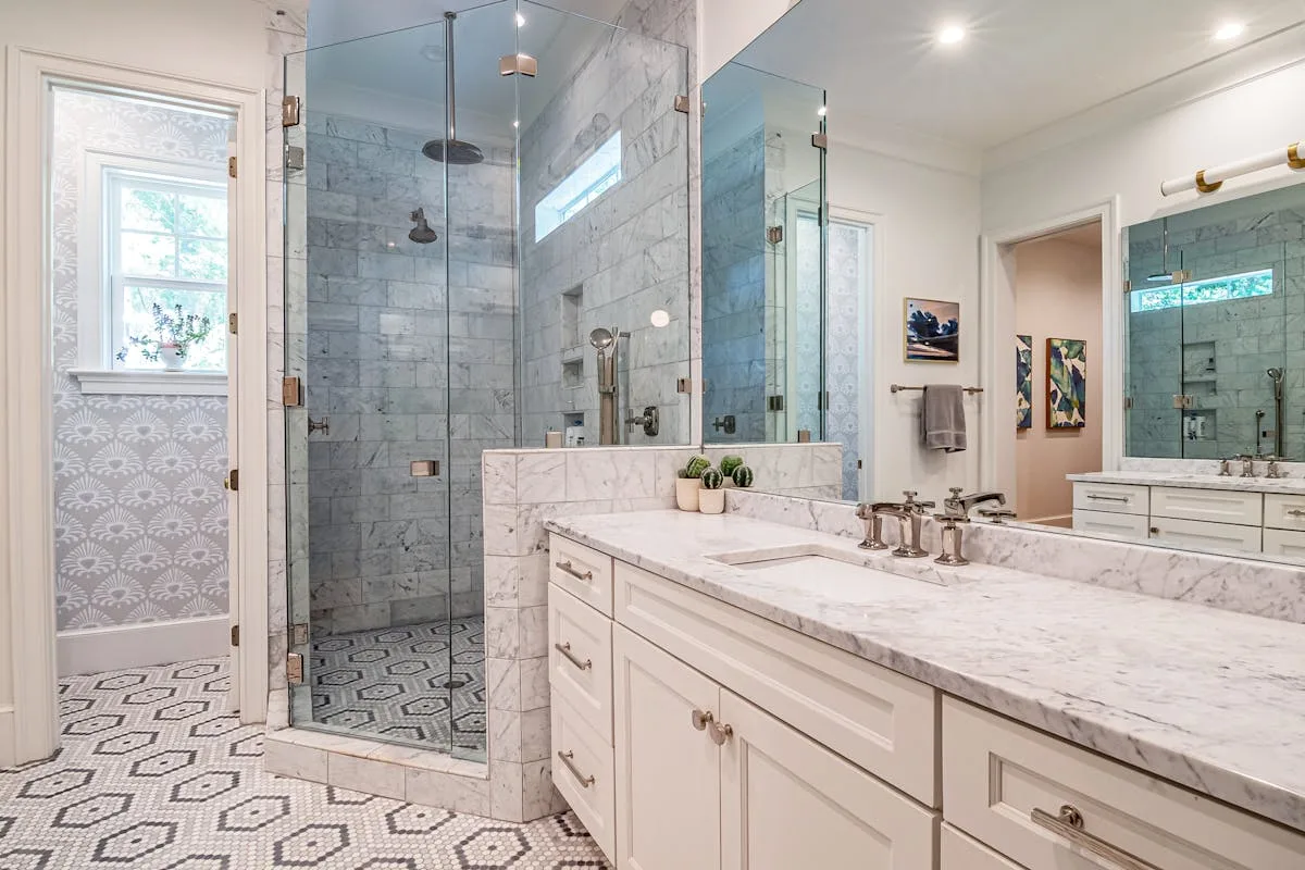 Bathroom with hex and marble pattern floor tile beside a marble vanity, mosaic detail visible
