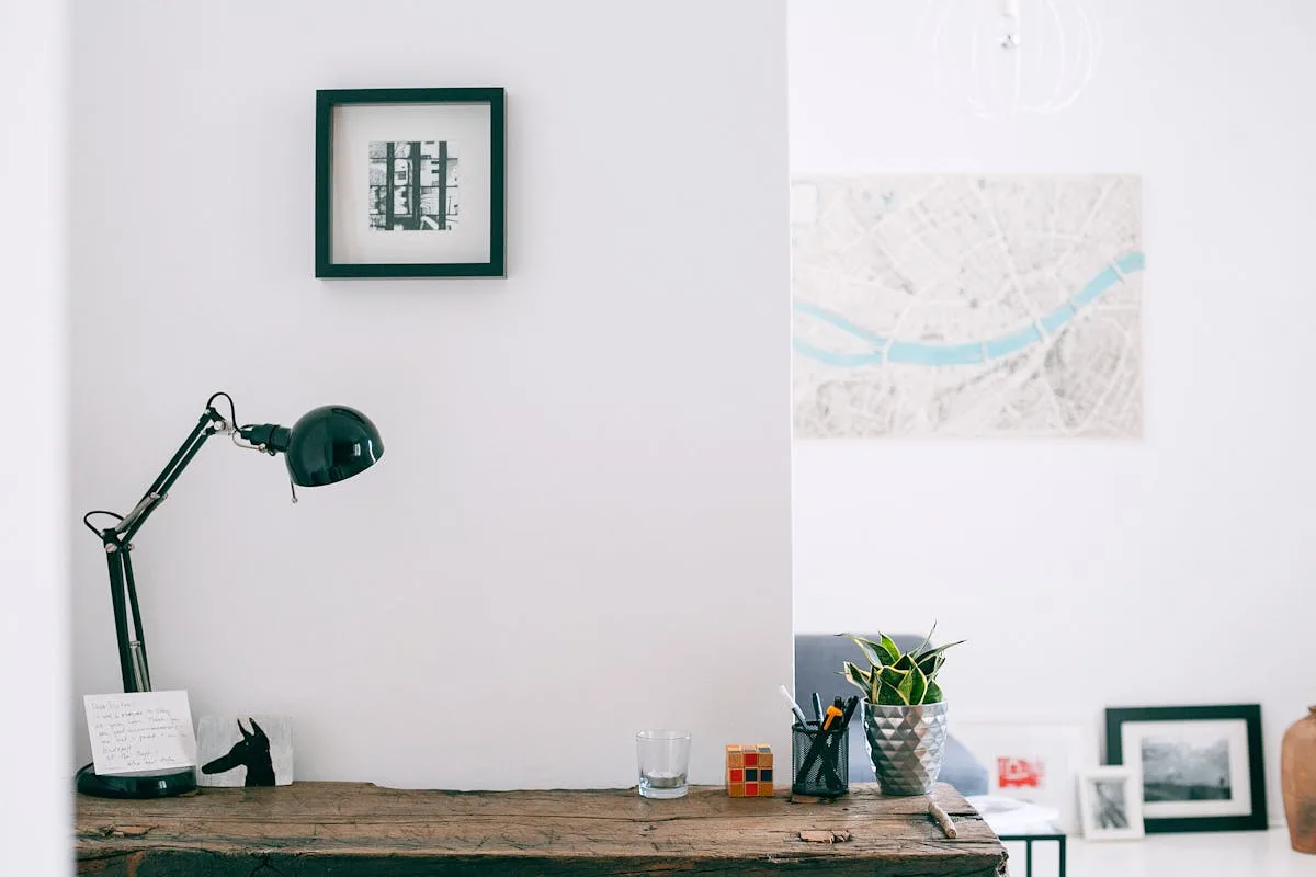 Home office desk and wall with framed art and a city map print on a white wall