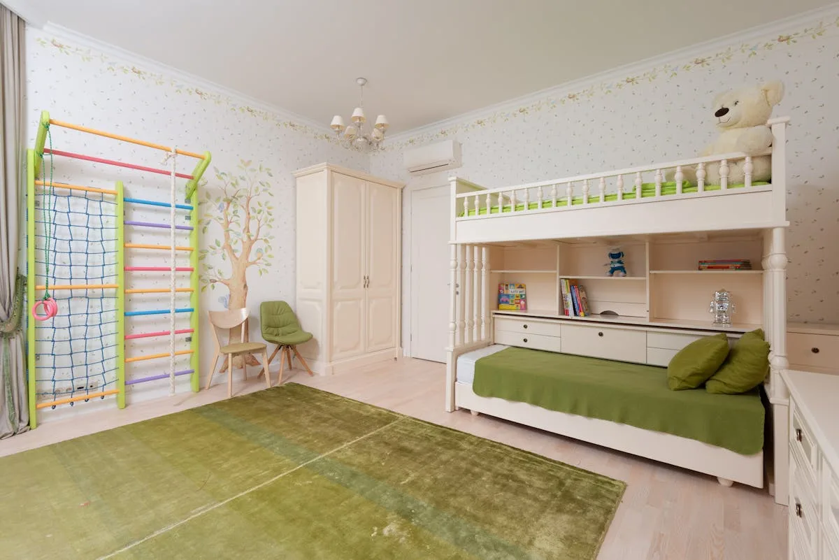 Child's bedroom with a tree wall decal, bunk bed and a green play rug