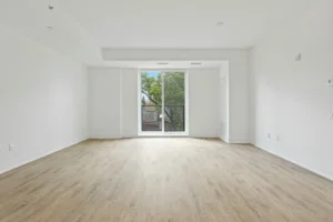Empty bright rental living room with neutral walls and light wood flooring on the first day of a new lease