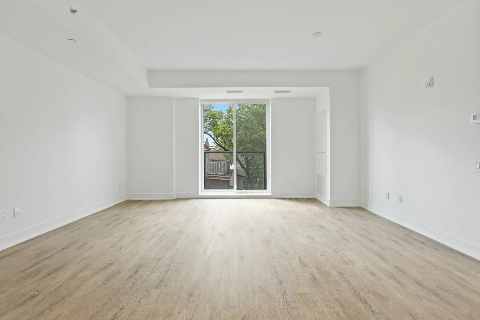 Empty bright rental living room with neutral walls and light wood flooring on the first day of a new lease