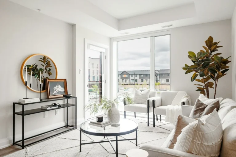 Bright small rental living room with leaning round mirror, neutral palette, and white walls