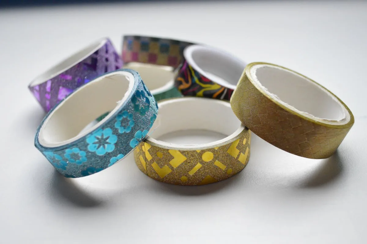 Colorful washi tape rolls stacked on a white surface, ready for wall decor