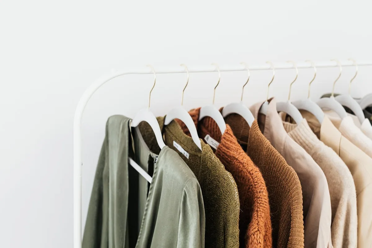 Neutral clothing on a hanging rack against a white wall
