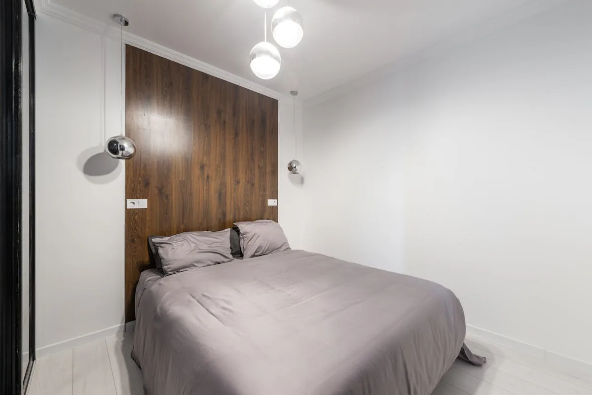 Small apartment bedroom with a low bed, wood accent wall and minimal styling