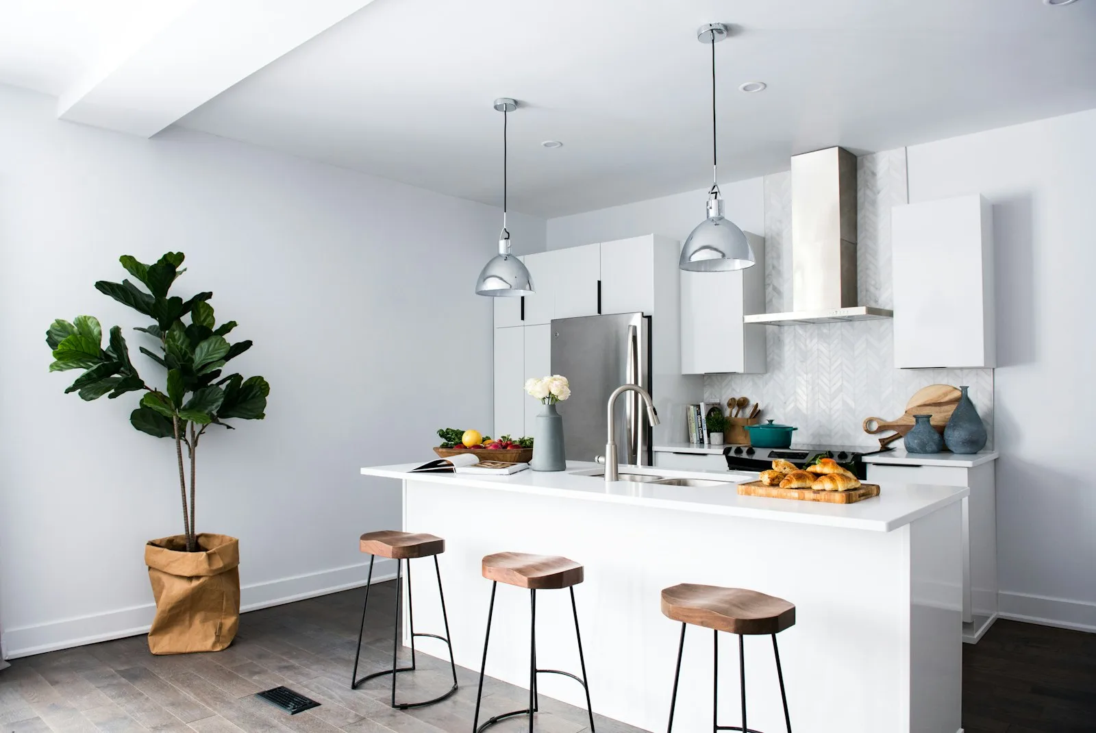 Bright small apartment kitchen with white cabinets, a plant, and clear counters