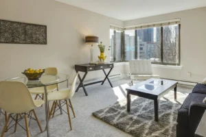 Small Apartment Living Room Ideas That Actually Work in a Tight Space Small apartment living room with a sofa, rug and city window in warm neutral light