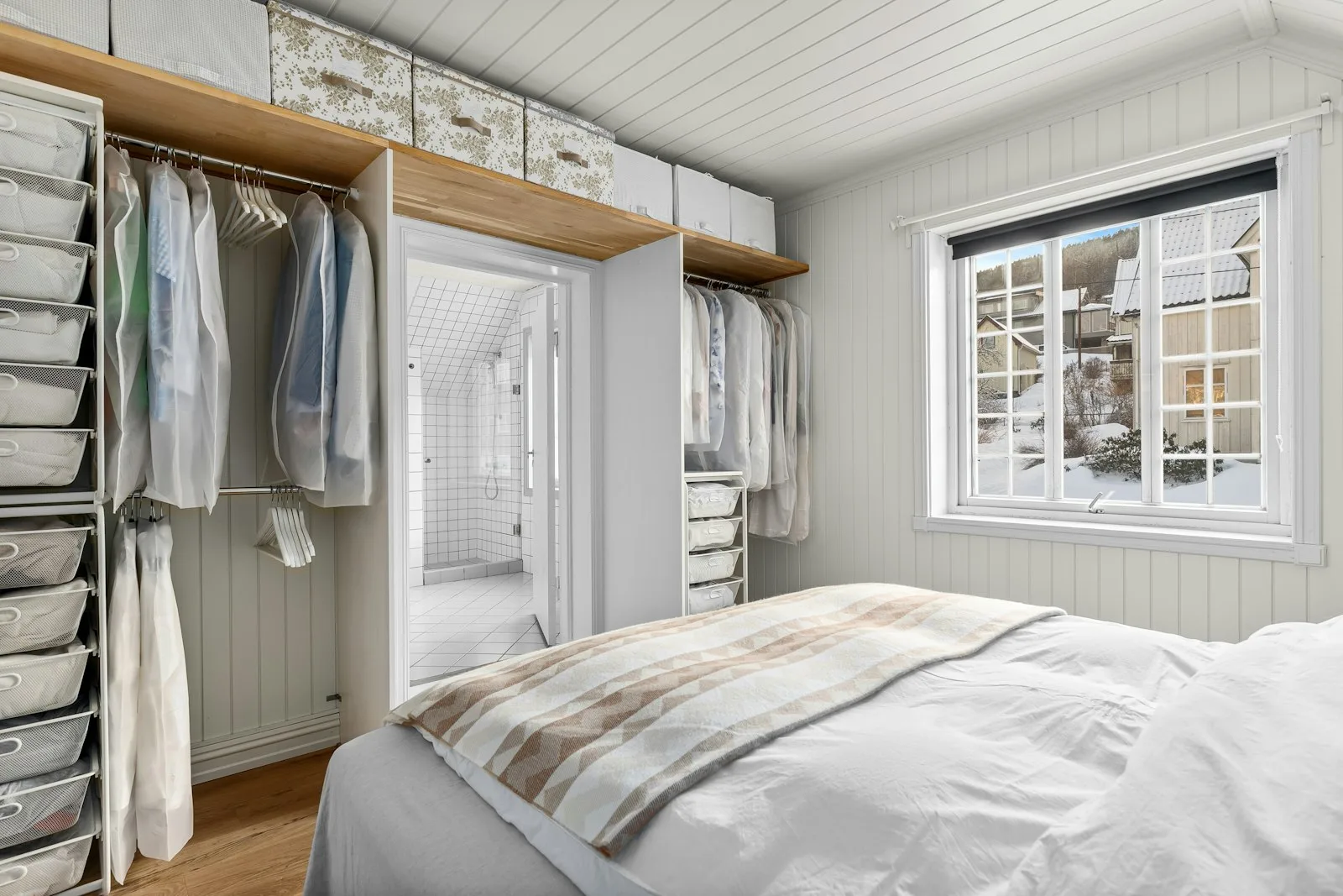 Small bedroom closet with drawers, hanging clothes, and storage boxes