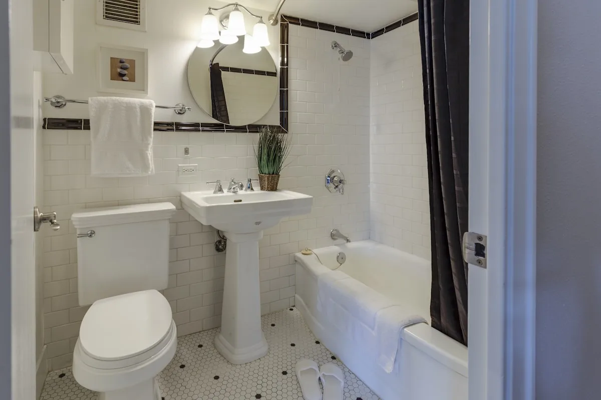 Compact rental bathroom with white subway tile, pedestal sink, and shower curtain