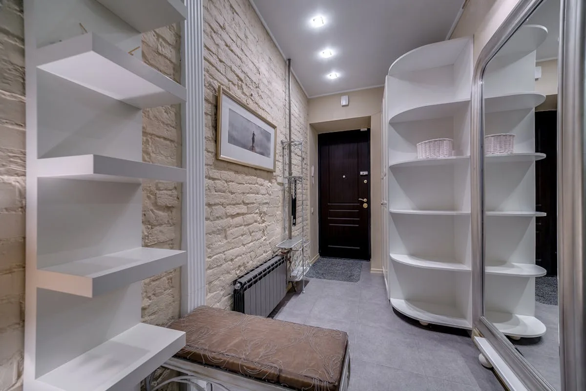 White wall-mounted shelving in a small apartment using vertical space for storage