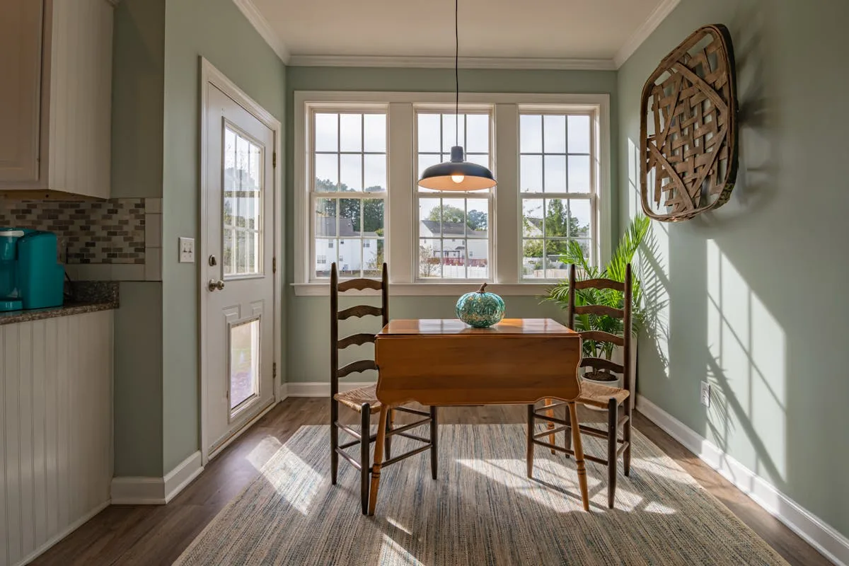Drop-leaf wooden dining table folded against the wall in a small bright room