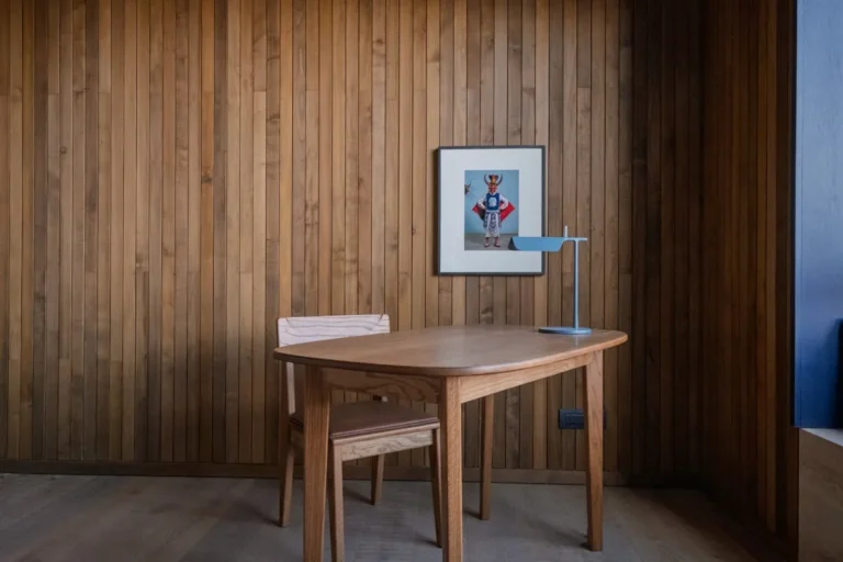 Compact walnut drop-leaf table set against a wood-panel wall in a small apartment