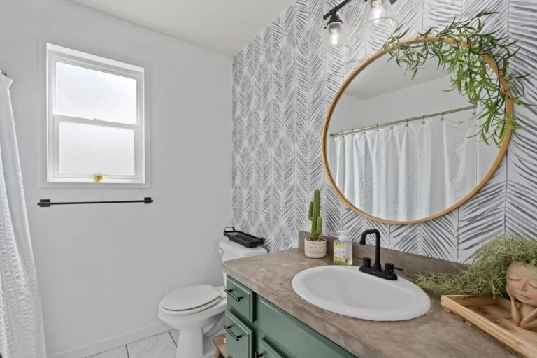 Small bathroom accent wall in soft palm-frond peel-and-stick wallpaper pattern next to sage vanity