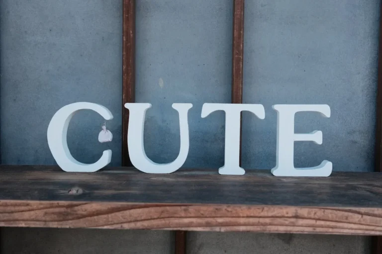 White block letters spelling CUTE on a rustic wooden shelf