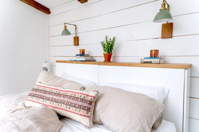 White shiplap accent wall in a cozy bedroom with brass sconces