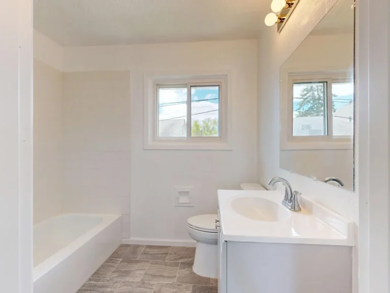 Simple bright bathroom with stone-look floor tile and a tub